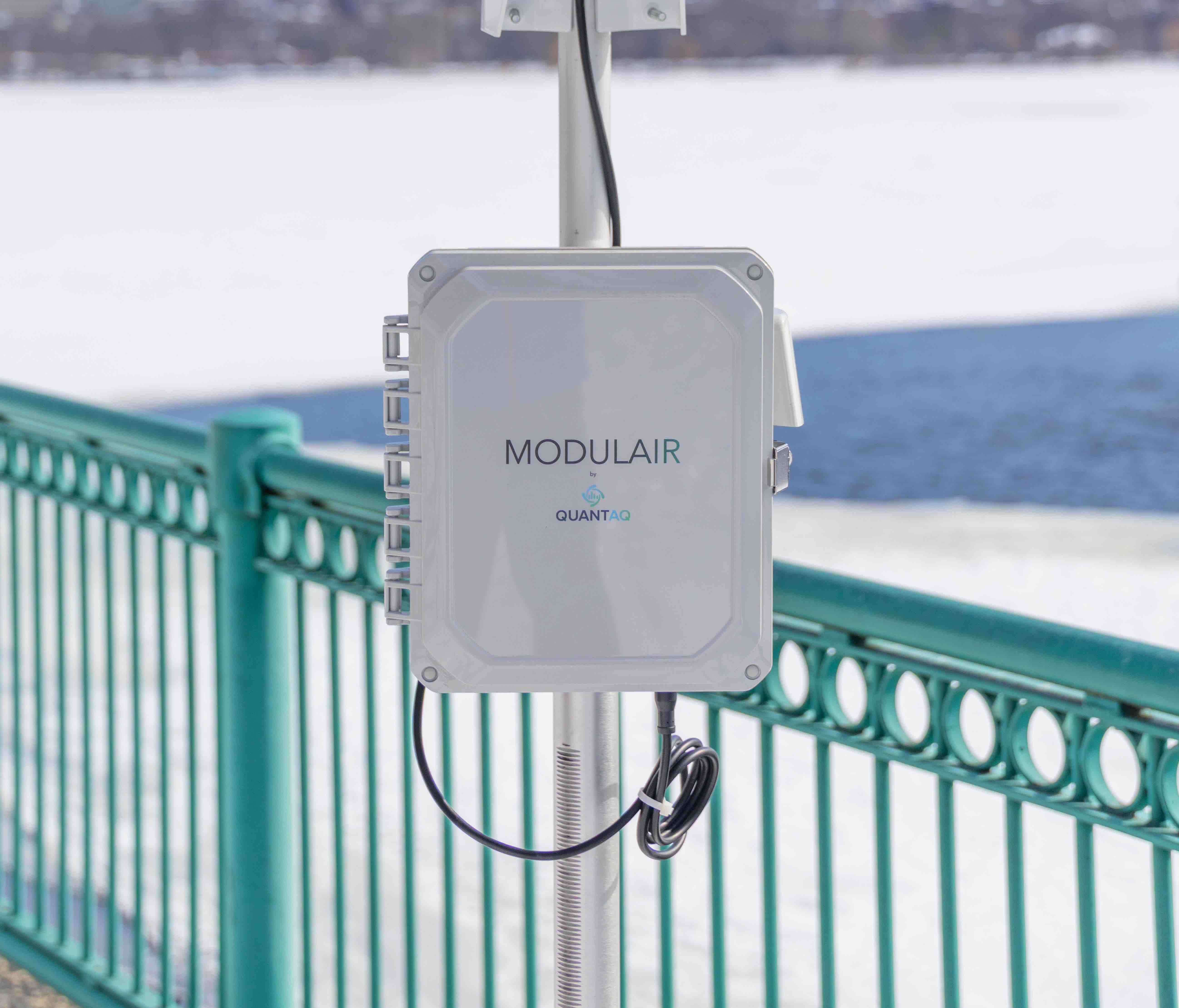 MODULAIR device on a pole with a weather station attached in front of a snowy river
